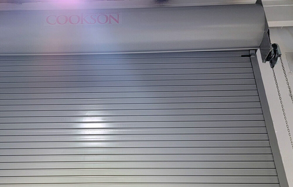 A closed silver metal roll-up door with COOKSON faintly visible at the top.